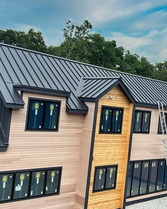 Two-story home with wood siding and a dark standing seam roof