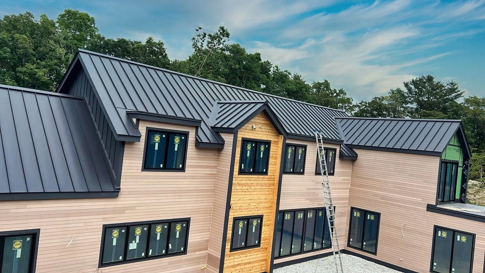 Dark standing seam roof on a two-story home with wood siding